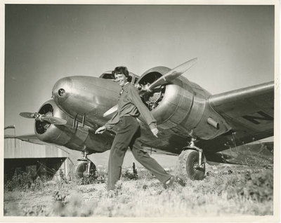 Amelia Earhart walking in front of her Lockheed Electra airplane, ca. 1930s