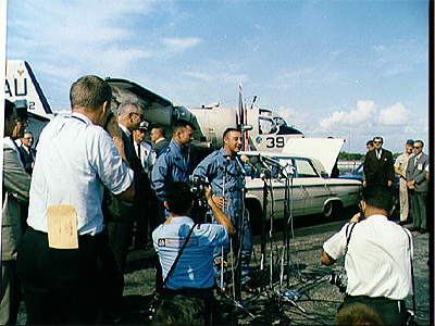 Astronauts John W. Young (left) and Viril I. Grissom stand before microphones at Cape Kennedy's skid strip during welcome back ceremonies for Gemini-3 crew.
